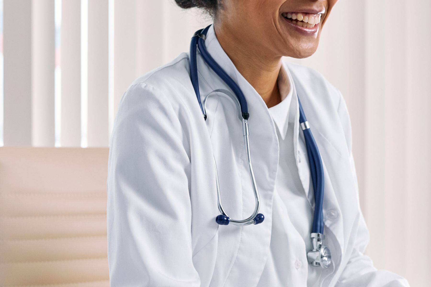 Smiling female doctor seated at a desk in a bright practice office