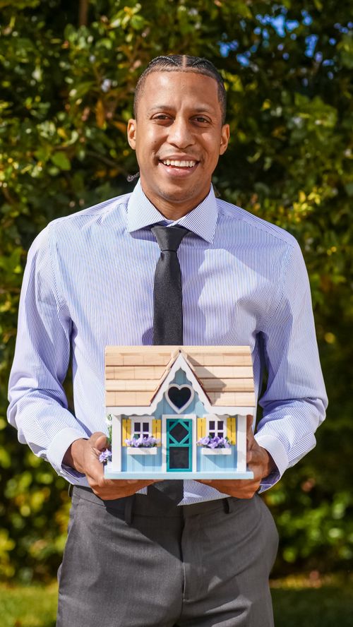 Free Professional realtor holding a small house model, symbolizing real estate and new home purchases. Stock Photo