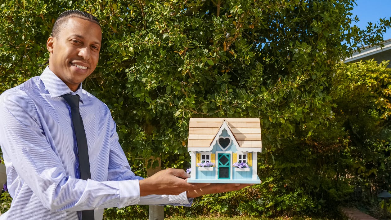 Free Man In Dress Shirt Holding A Miniature Wooden House Stock Photo