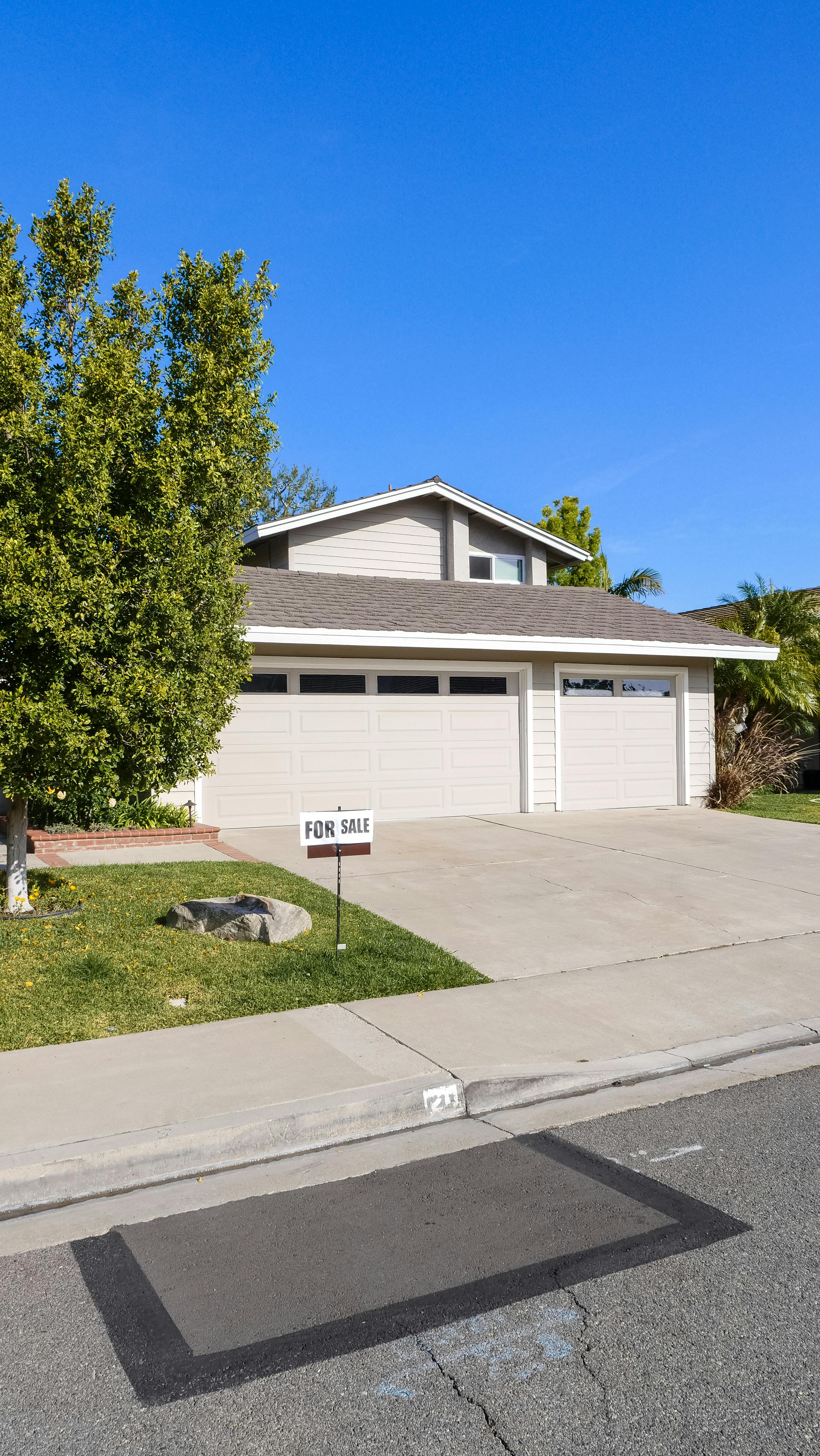 Alt Text: House with for sale sign in front yard