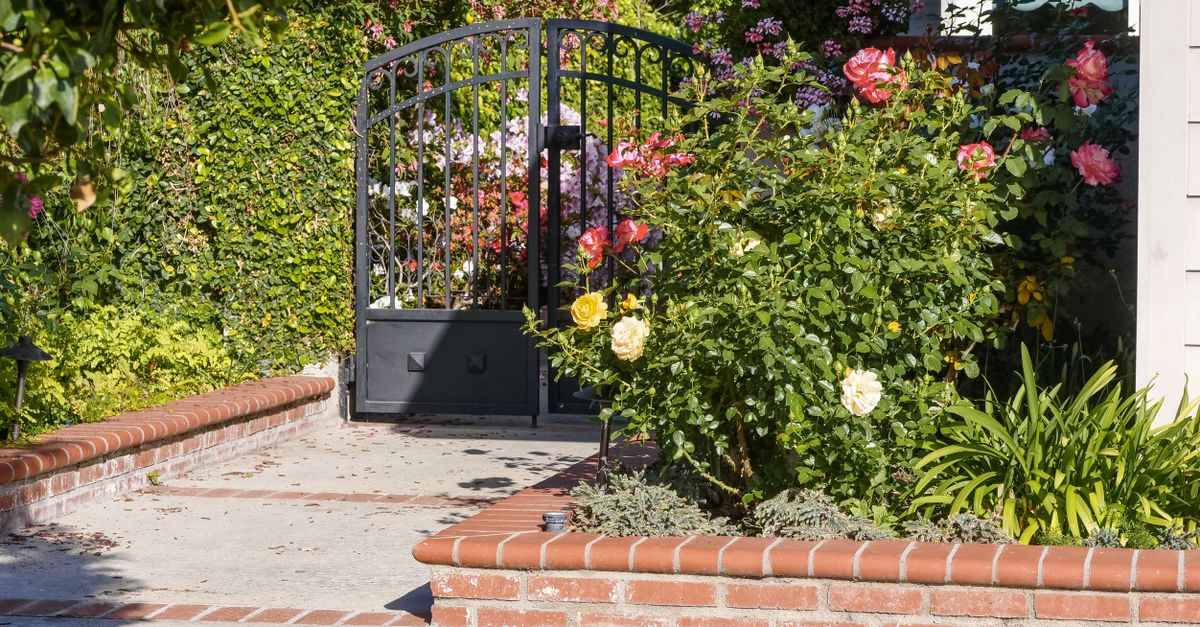 A delightful garden featuring vibrant roses and an elegant iron gate, perfect for residential appeal.