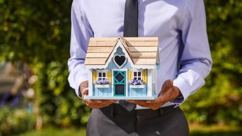 Free Businessman holding a model house symbolizing real estate investment. Stock Photo