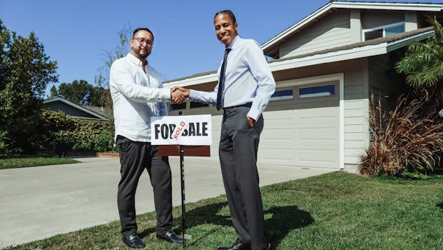 Two men shake hands in front of a new home with a sold sign, symbolizing a successful real estate deal.