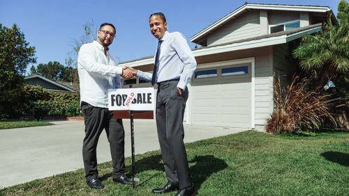 Free Two men shaking hands in front of a sold house, symbolizing a successful real estate transaction. Stock Photo