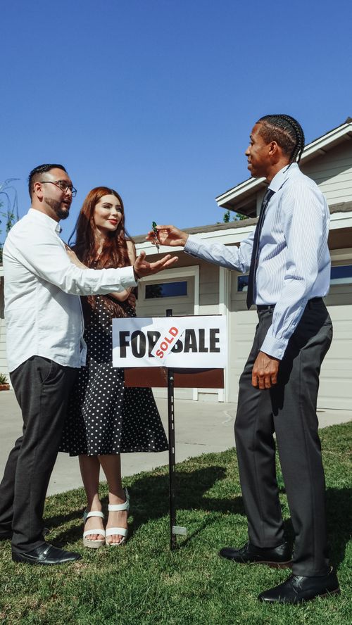 Free Couple receiving keys from realtor in front of newly sold house. Perfect real estate imagery. Stock Photo