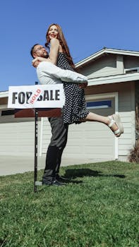 A joyful couple celebrates buying their new house with a 'Sold' sign.