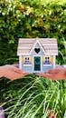 People Holding a Miniature Wooden House