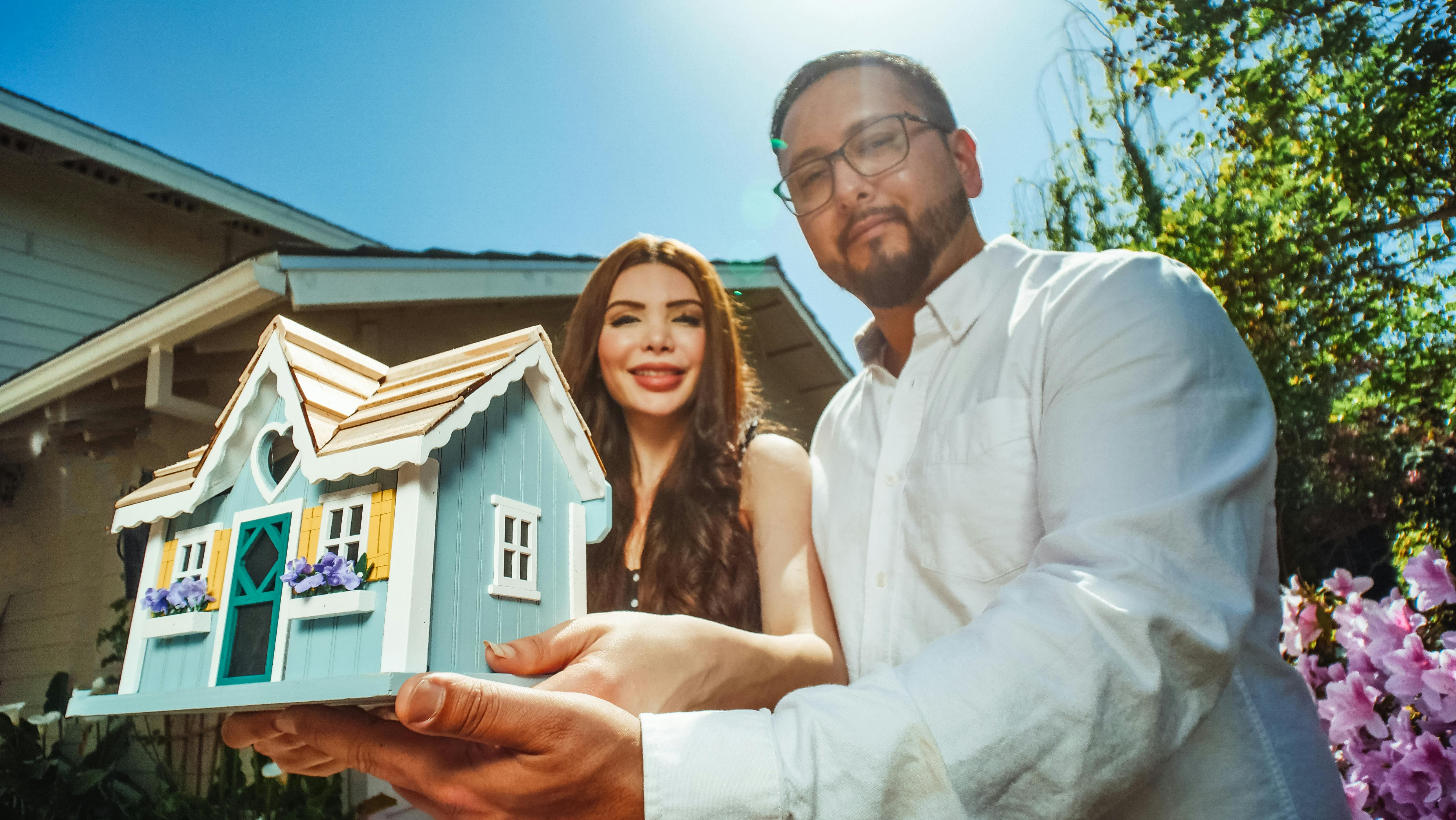 couple holding a miniature house