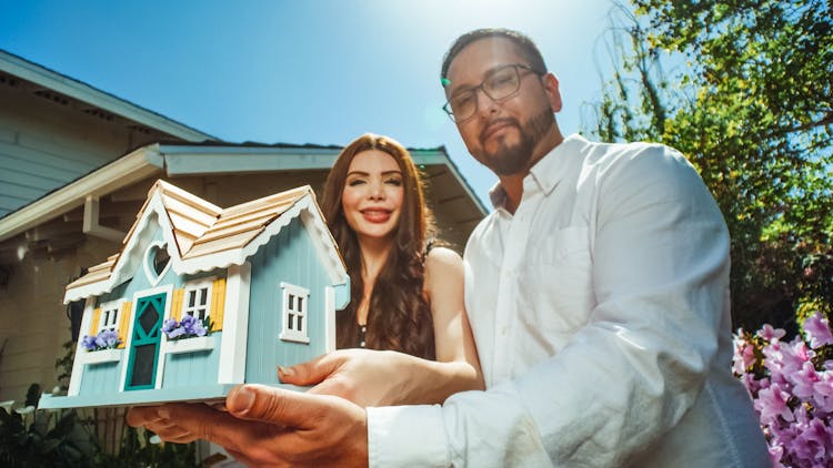 Couple Holding A Miniature House