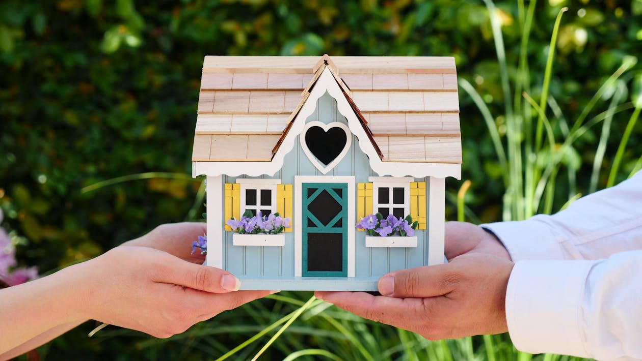 Photo by Kindel Media from Pexels: https://www.pexels.com/photo/people-holding-miniature-wooden-house-7578939/