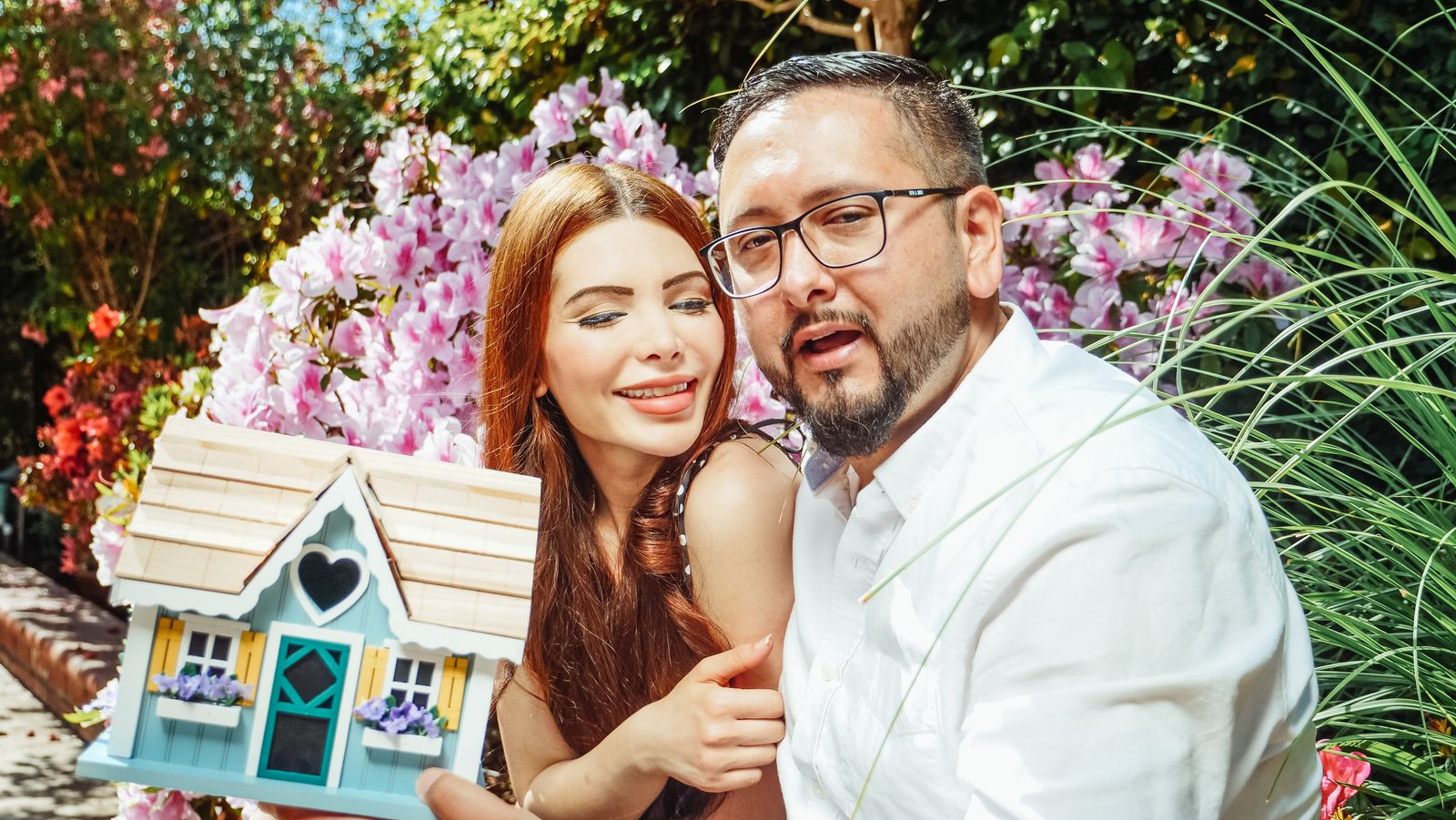 Couple smiling while holding a small house figurine after planning a downsize
