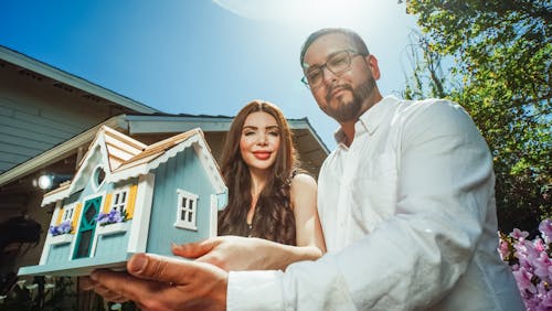 Man and Woman Holding a Miniature House