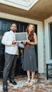 Man and Woman Holding a Blackboard In Front of their House