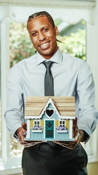 Smiling agent presents a charming miniature house, symbolizing real estate opportunities.