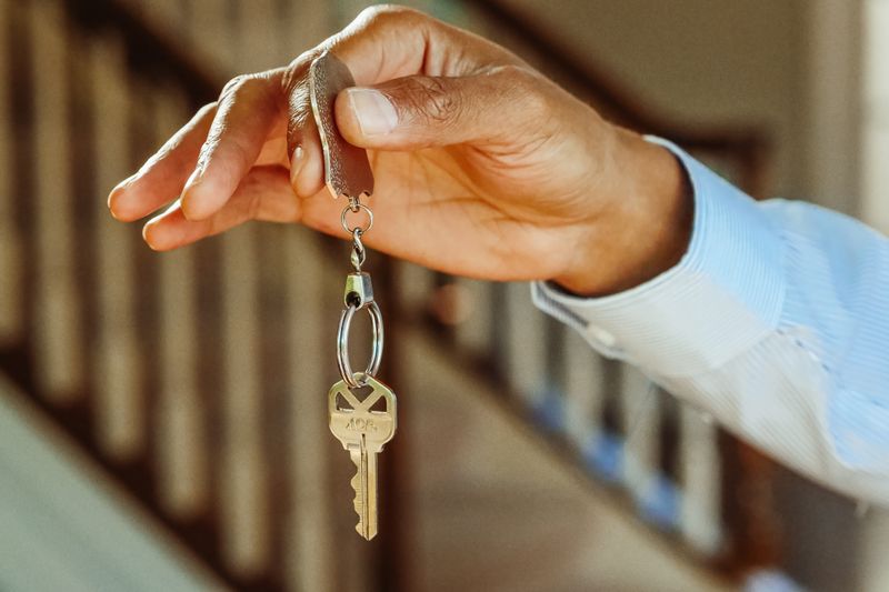 A close-up shot of a hand holding a house key, indicating new ownership or rental.