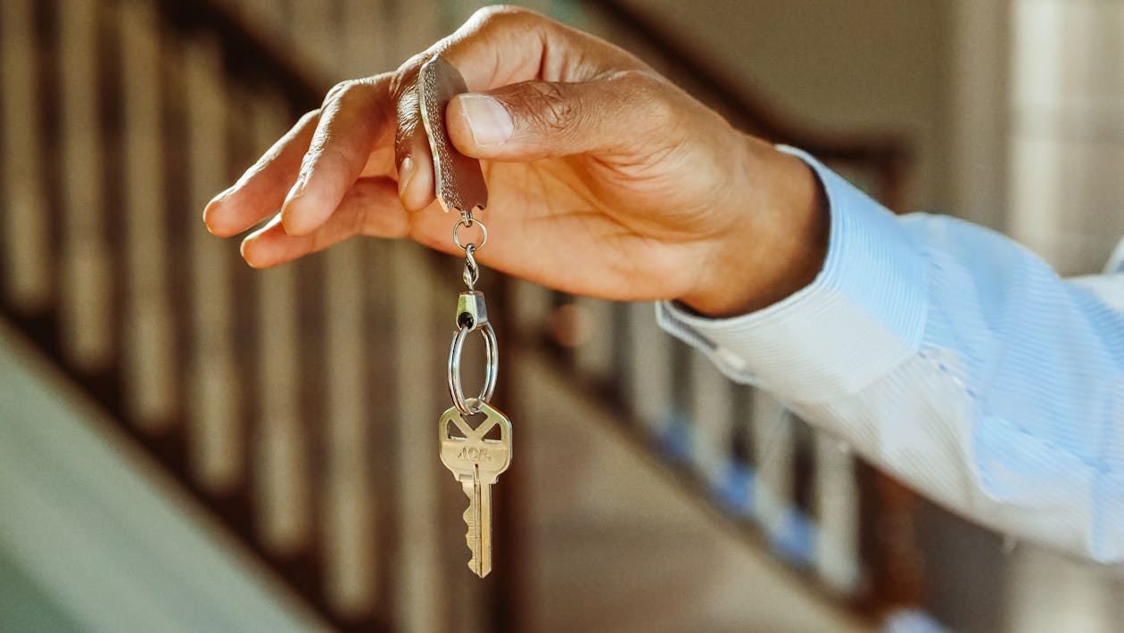 Free Person Holding a Silver Keychain with a Key Stock Photo