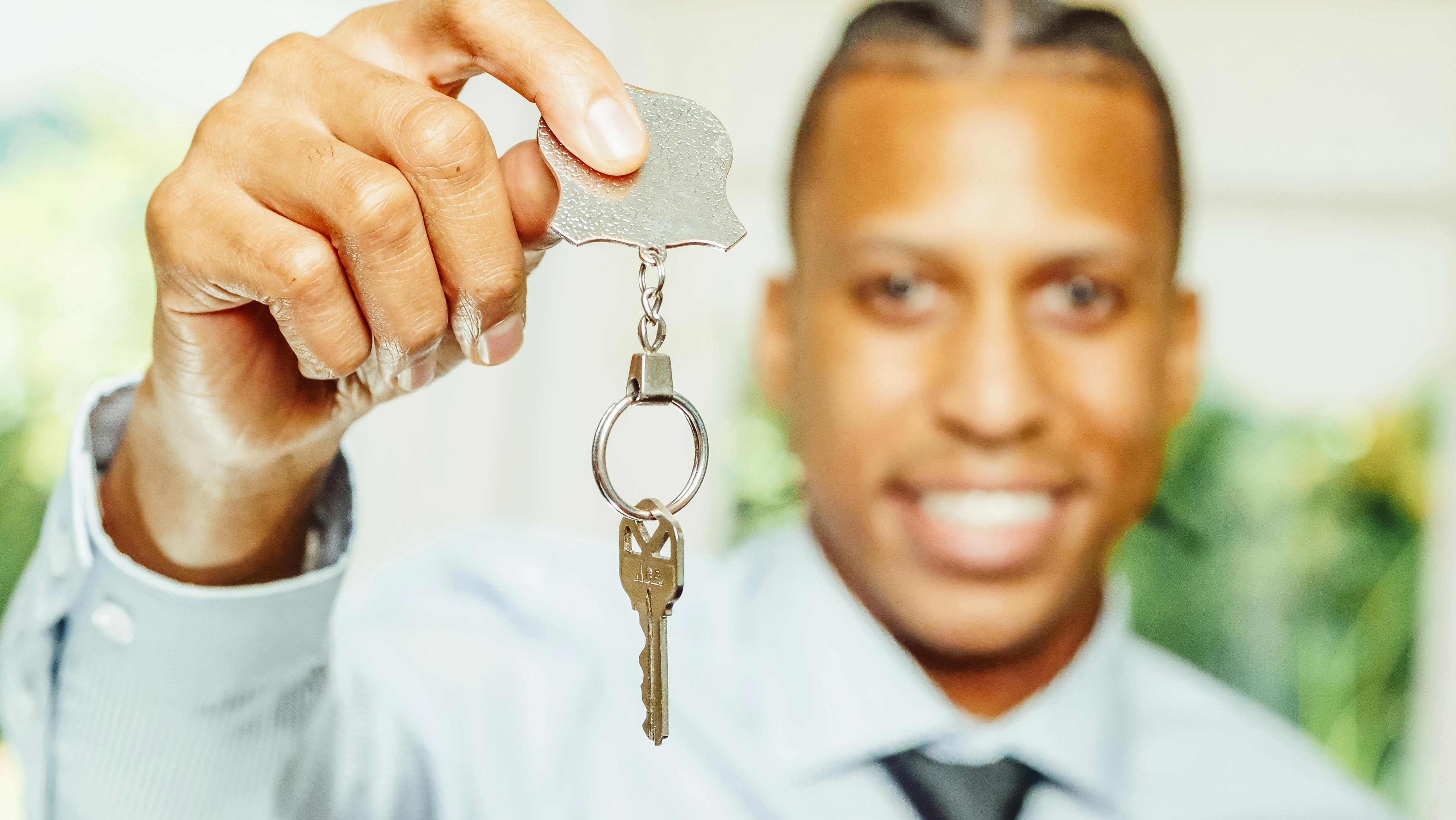 man in white dress shirt holding a silver key