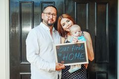 Young family holding sign celebrating their first home purchase. Joyful and heartwarming moment.
