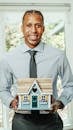 Man in Blue Dress Shirt Holding a Miniature House