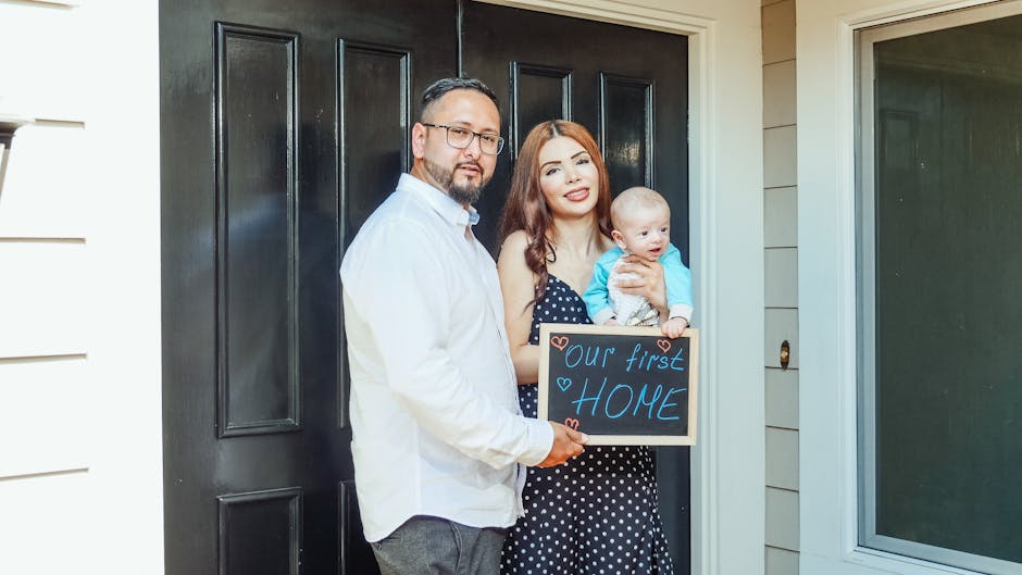 Young family with baby holding a sign 'Our First Home' at doorstep, symbolizing new beginnings.