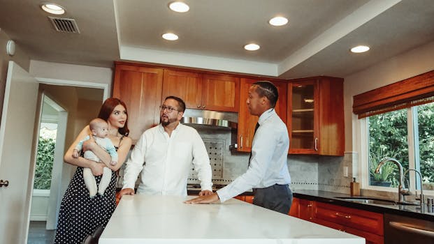 A young family tours a modern kitchen guided by a real estate agent.
