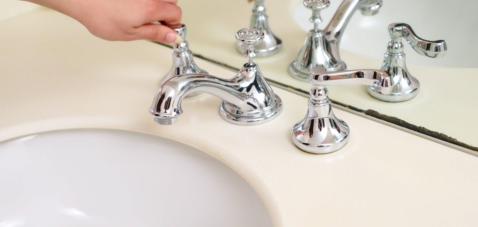 Hand adjusting a chrome bathroom faucet