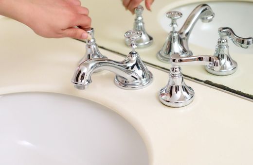 Hand adjusting a chrome bathroom faucet