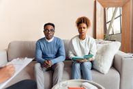 A Couple Frowning while Sitting at a Couch