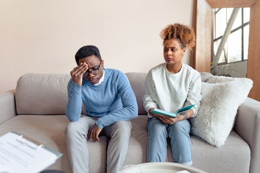 A Couple Frowning while Sitting at a Couch
