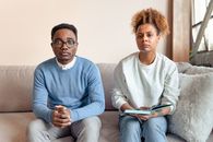 A Couple Frowning while Sitting at a Couch