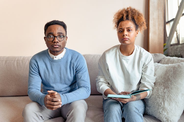 A Couple Frowning While Sitting At A Couch