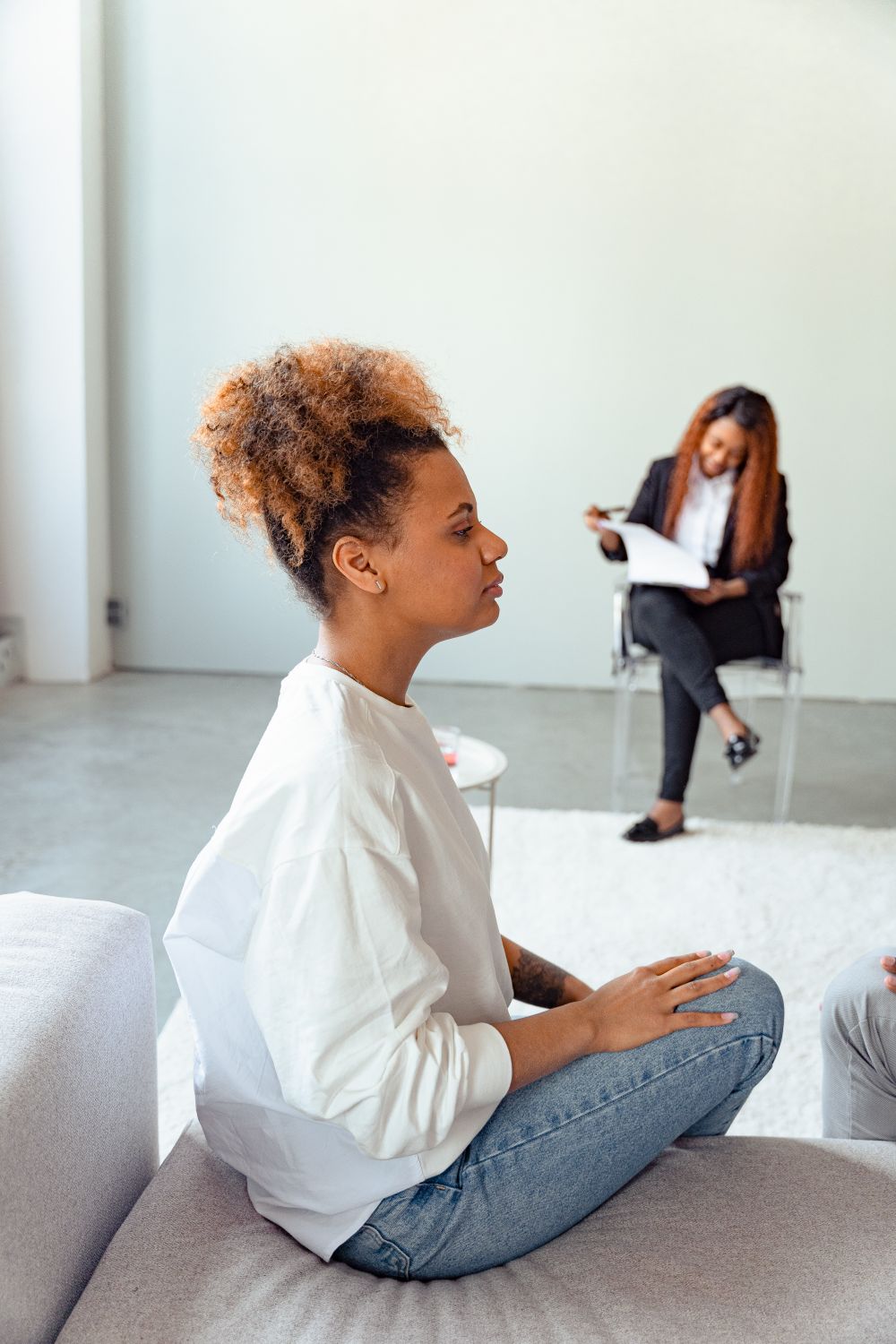 Woman in White Long Sleeve Shirt Sitting on Gray Couch · Free Stock Photo
