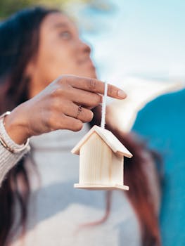 Close-up of a woman holding a mini wooden house, symbolizing new home purchase.