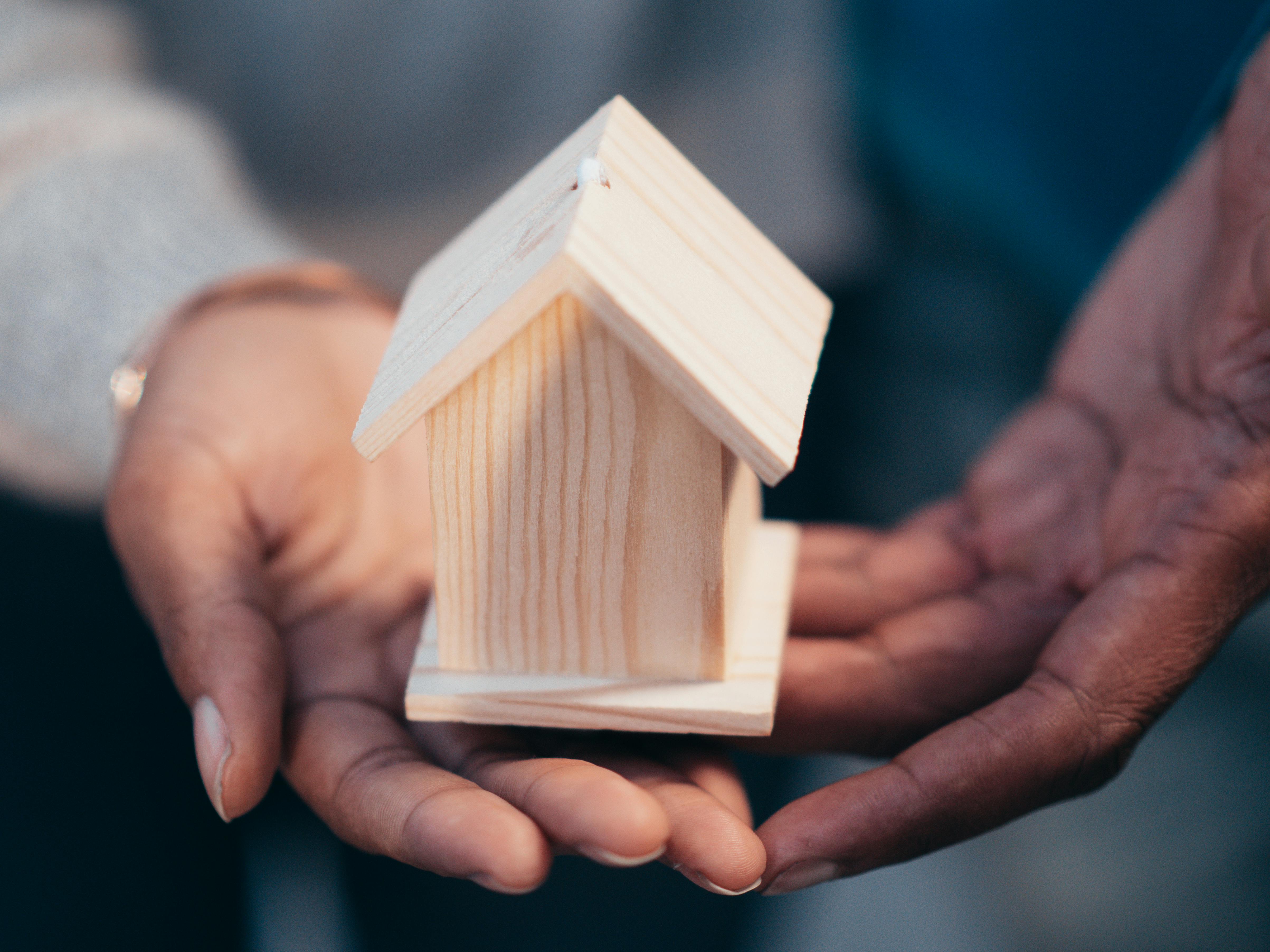 person holding miniature wooden house
