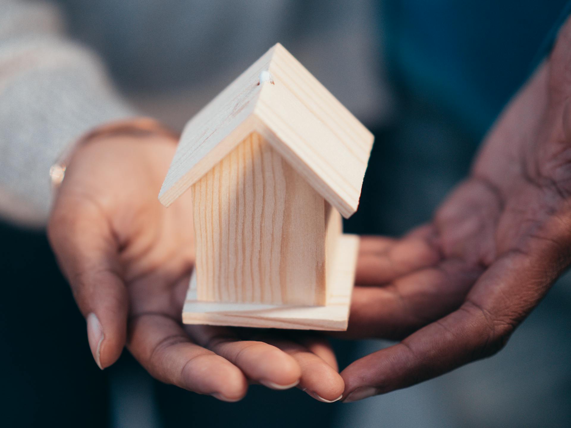 Person Holding Miniature Wooden House