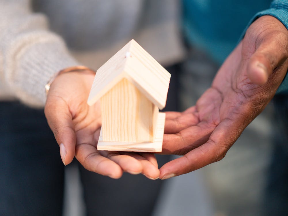 A person holding a model house, representing multi-family property investment supported by bridge loans.
