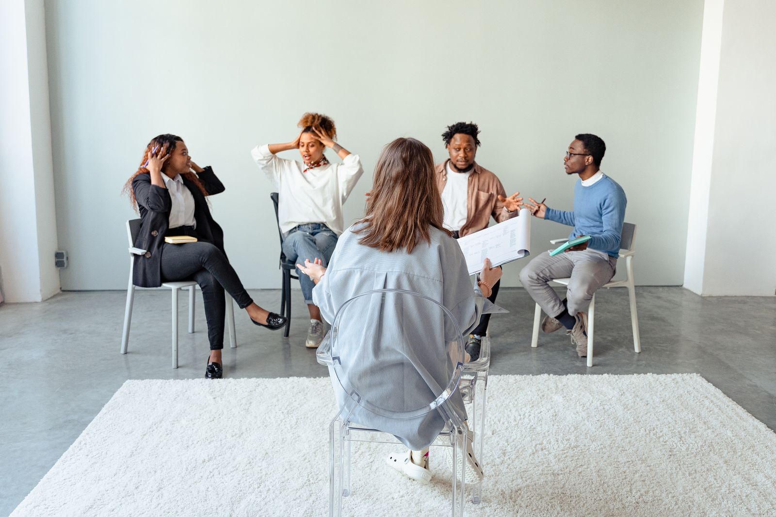 Adults seated together in a group therapy session, listening to one another