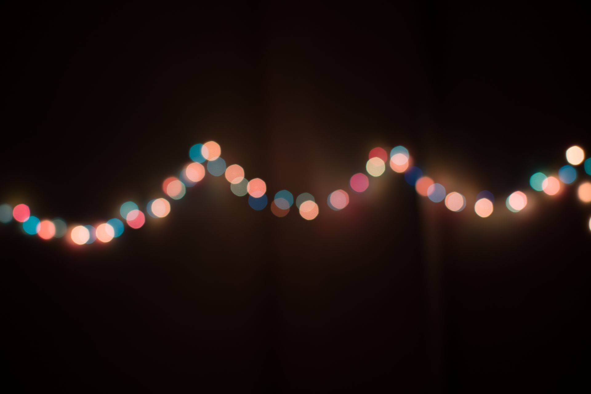 Defocused string lights creating a colorful bokeh effect on a dark background, evoking a festive mood.