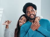 Joyful couple proudly holding keys to their new home, symbolizing fresh beginnings.