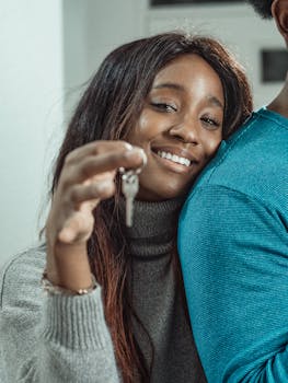 Smiling African American woman celebrating new home purchase by showing a key indoors.