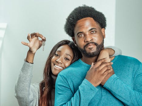 Smiling couple celebrates receiving keys to their new home indoors.