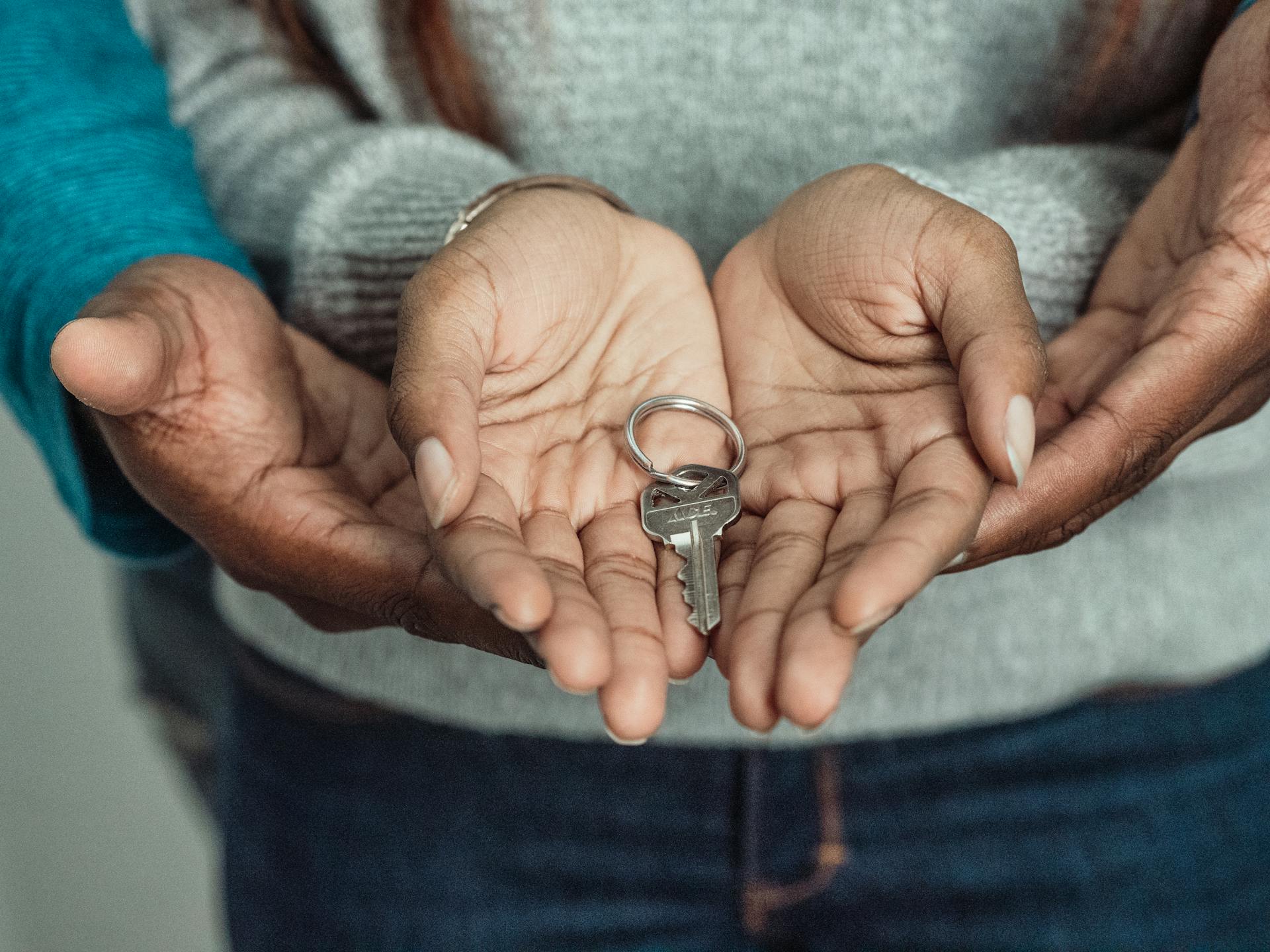 Close-up of a couple sharing a key, symbolizing new home ownership.