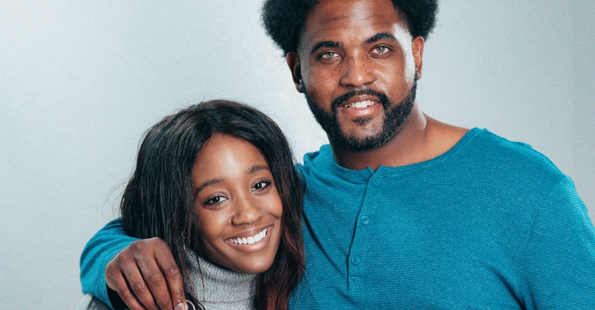 Smiling African American couple holding keys, celebrating home ownership.