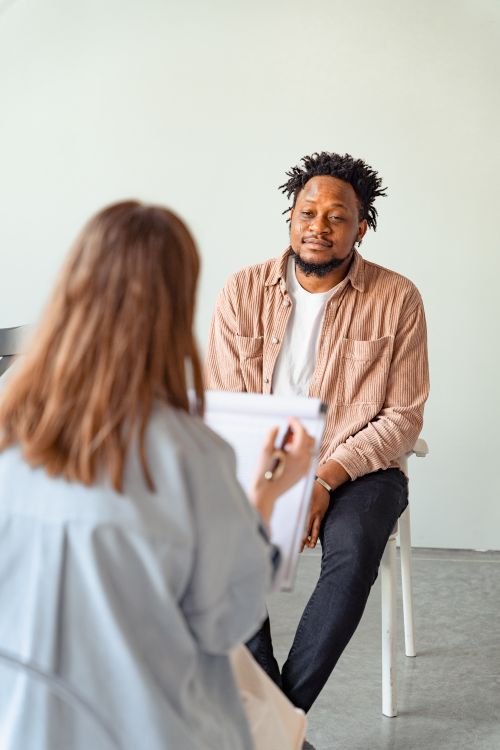 Free A psychotherapy session between a male patient and a female counselor discussing mental health. Stock Photo
