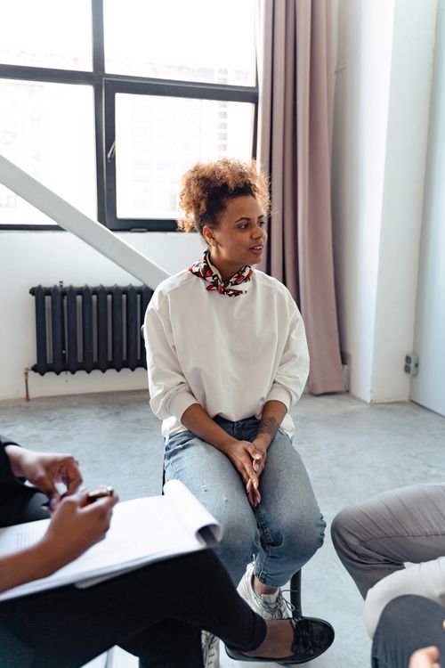 Free A woman participates in a group therapy session indoors, engaging with peers. Stock Photo
