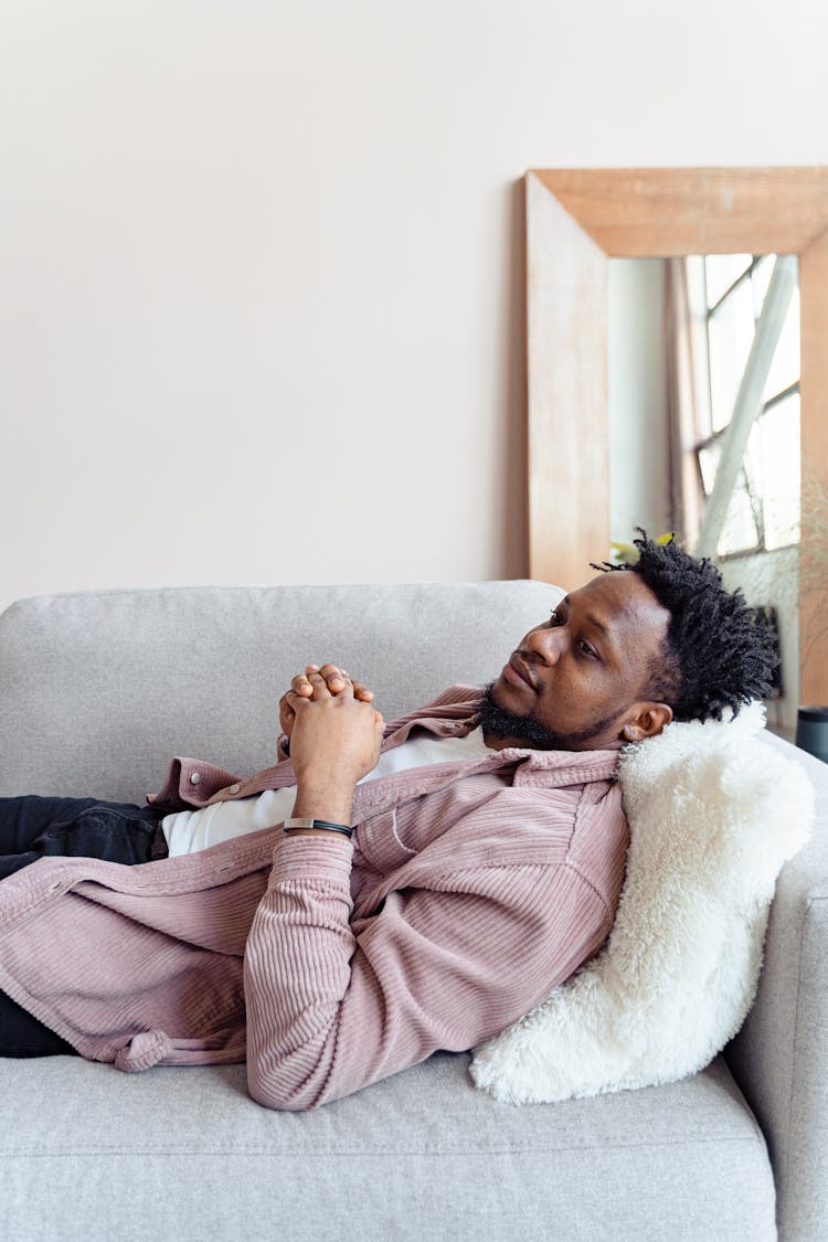 Man In Pink Corduroy Jacket Lying On Couch