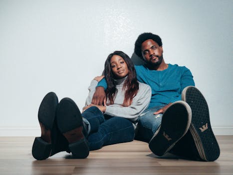 Happy couple sitting on the floor, embracing in their new home with smiles.