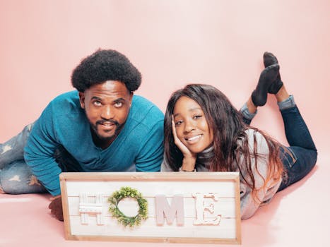A joyful couple lying together, celebrating their new home with a decorative sign.