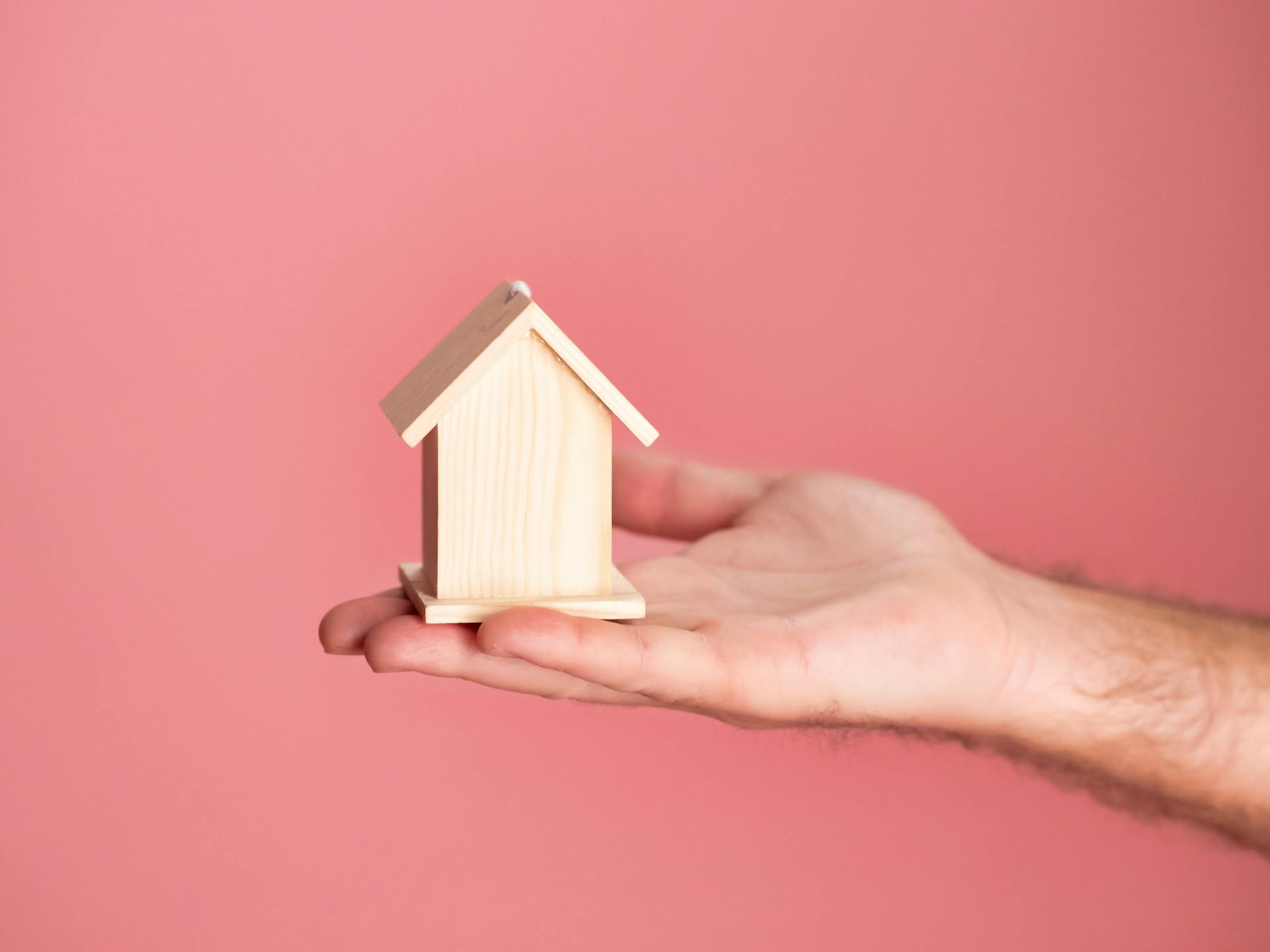 Une maison miniature en bois sur la paume d'une personne