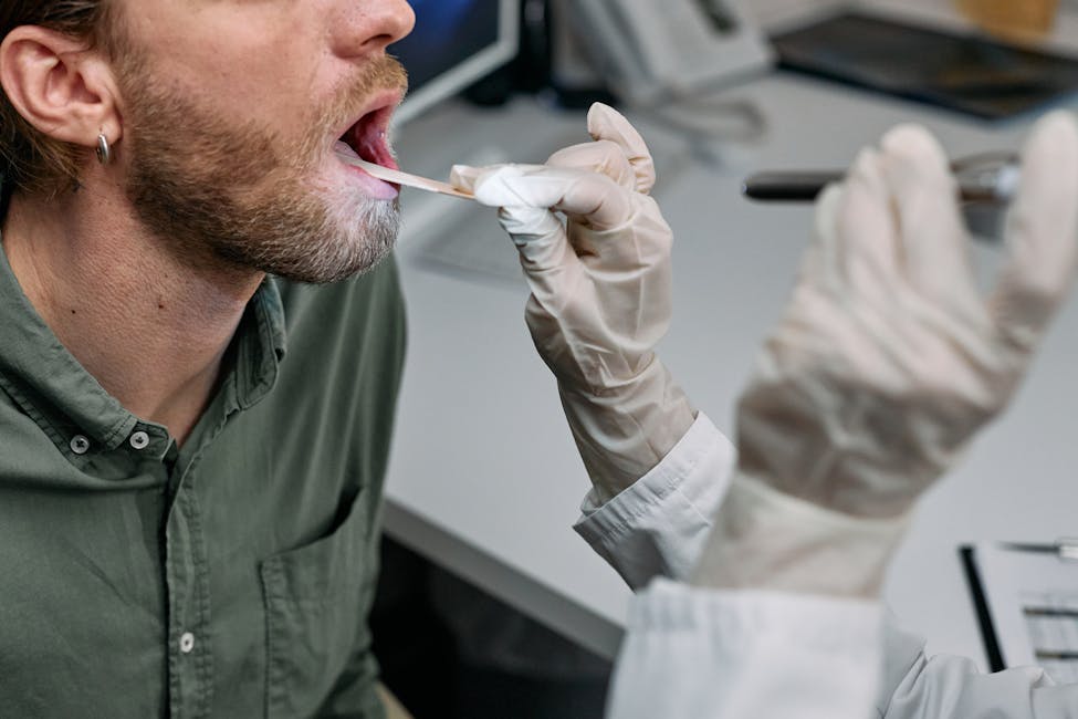 Close-up of a doctor examining a patient's throat with a tongue depressor in a clinical setting.